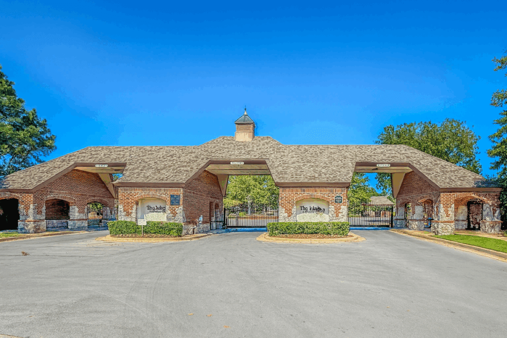 Gated brick entrance to The Lakes at Indian Springs in Indian Springs Broken Arrow on a clear blue day.