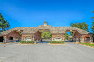 Gated brick entrance to The Lakes at Indian Springs in Indian Springs Broken Arrow on a clear blue day.