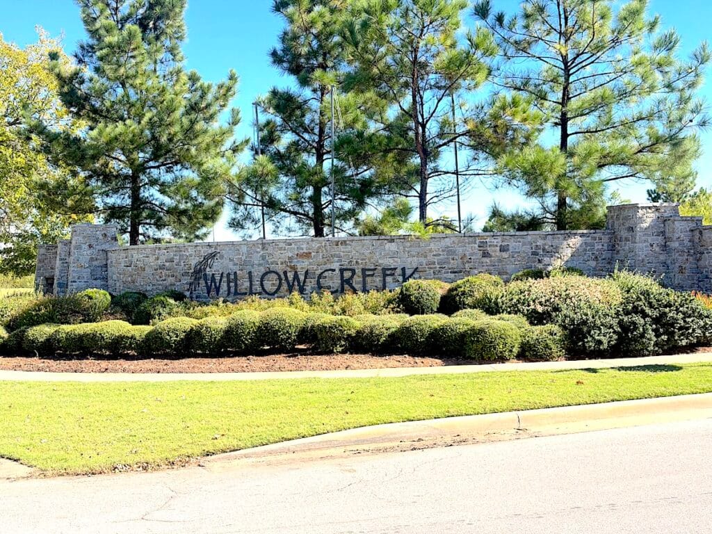 Entrance monument sign at Willow Creek Estates Bixby OK with stone wall and landscaped greenery.