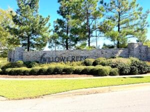 Entrance monument sign at Willow Creek Estates Bixby OK with stone wall and landscaped greenery.