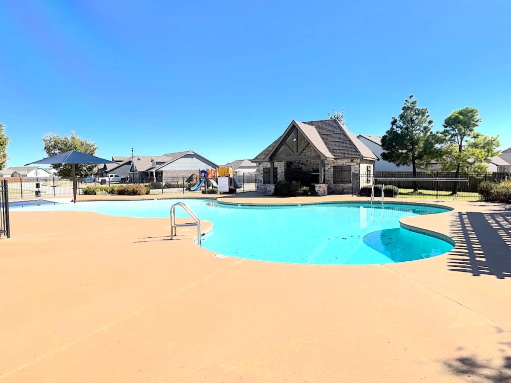 Gated community pool with surrounding patio and cabana in Bixby Oklahoma neighborhood.